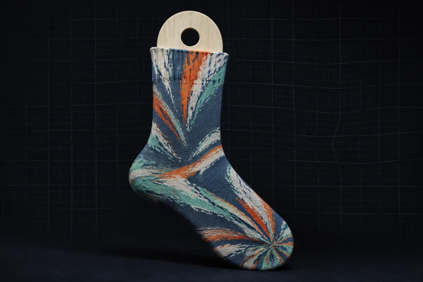 Oversized motif on a sock form. One large shape has one edge to distort instead of hundreds. Modelled stretch, not a photograph of a worn sock.