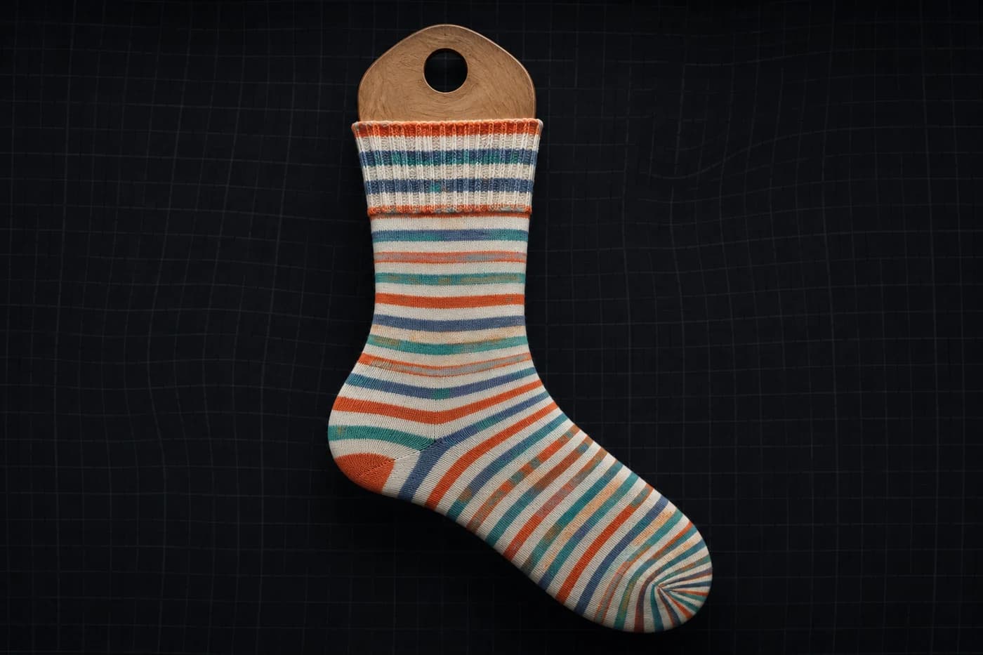 Equal bands on a sock form. Even flat. At the cuff the bands open; at the toe they close. Modelled stretch, not a photograph of a worn sock.