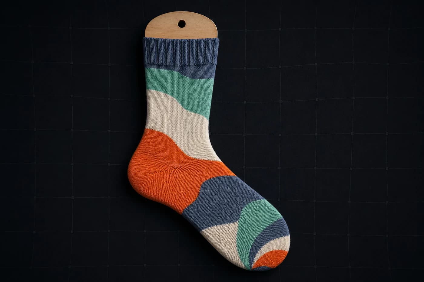 Colour-block wave on a sock form. Wide areas, soft edges, low period. Little for stretch to bite on. Modelled stretch, not a photograph of a worn sock.