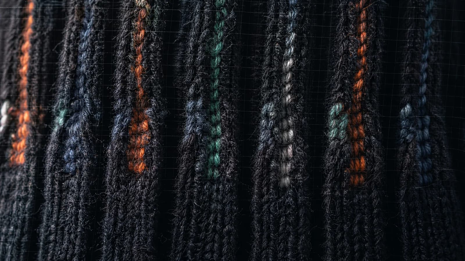Extreme macro of a relaxed ribbed knit cuff, deep vertical ribs at rest.
